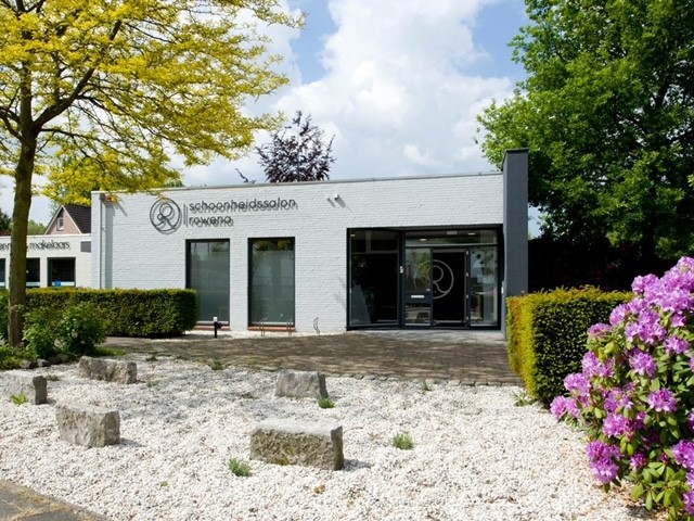 De voorgevel van Schoonheidssalon Rowena aan de Baerdijk met bloeiende rododendron