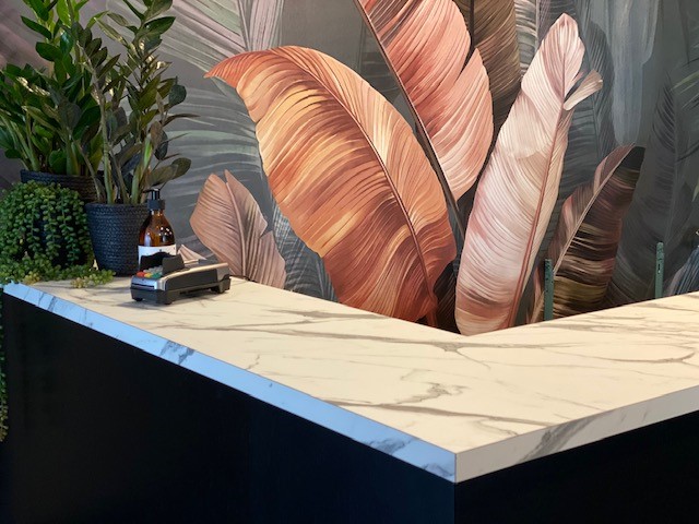 Balie met marmerlook voor een wand met geschilderde bladeren